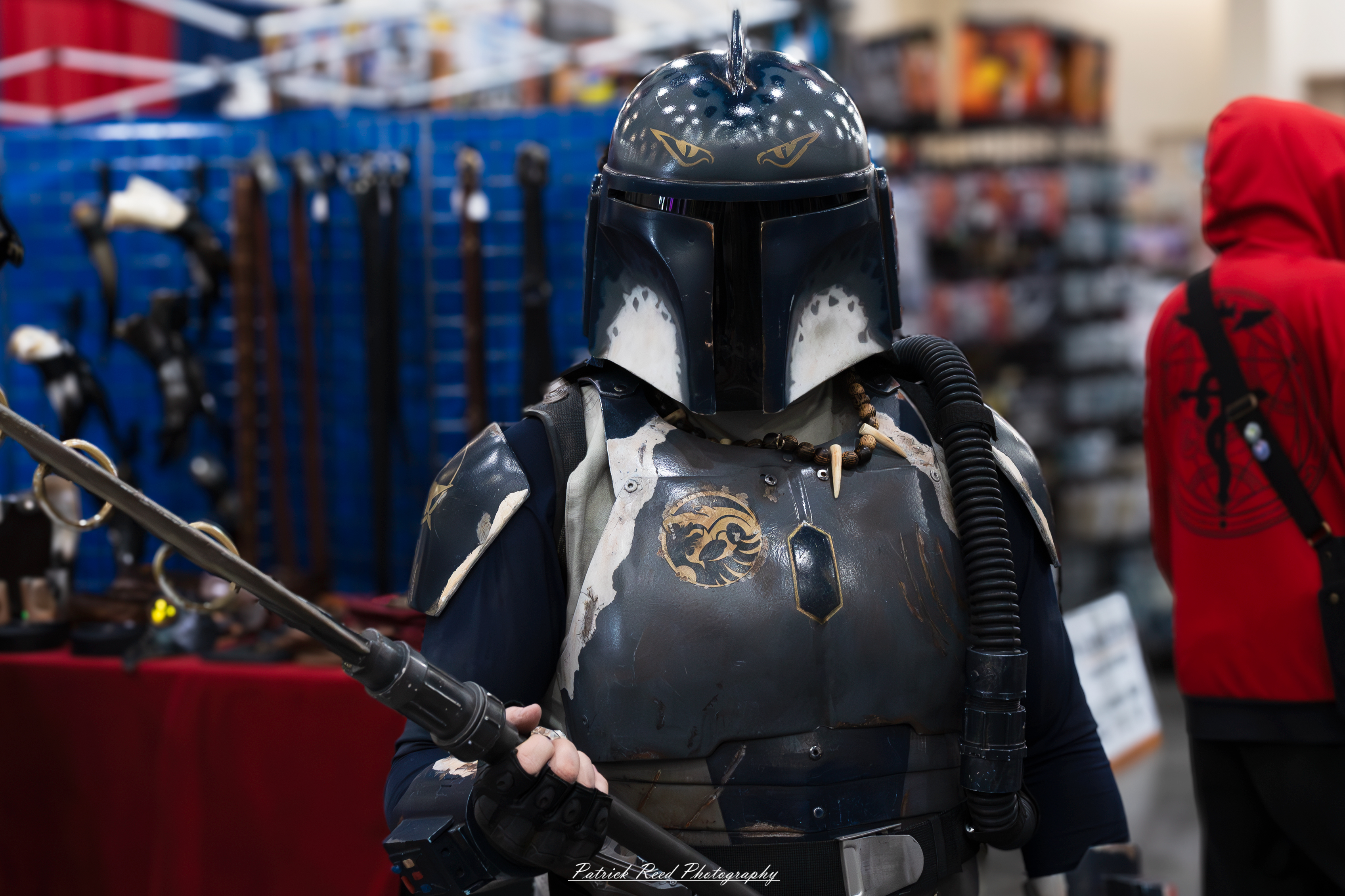 "A cosplayer wearing dark blue Mandalorian armor with a helmet featuring a T-shaped visor, standing confidently in a striking pose, evoking the Star Wars universe."